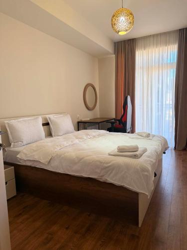 a bedroom with a large bed with a chair and a window at Well House Cozy 2BR in Tbilisi City