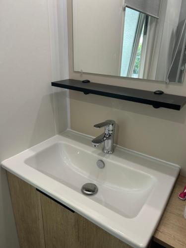 a white sink in a bathroom with a mirror at Mobilhome 592 FUNPASS NON INCLUS in Gastes