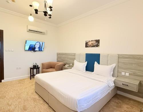 a bedroom with a large bed and a chair at سديم الفخر 2 للشقق الفندقية in Taif