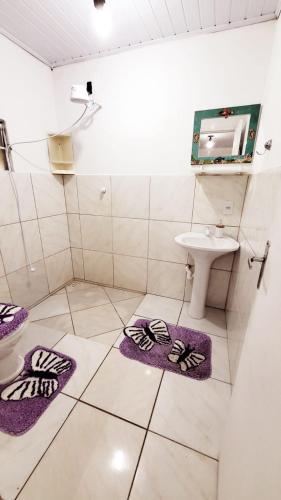 a bathroom with purple mats on the floor and a sink at paraiso da lagoa in Imbituba