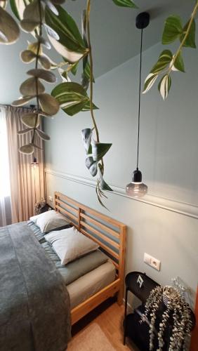 a bedroom with a bed with a plant on the wall at Fukša Saules dzīvoklis in Madona