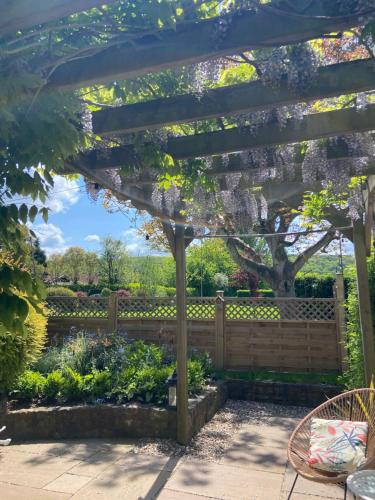 a pergola in a garden with a fence at The Nookery in Winscombe