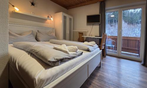 a large white bed in a room with a window at Pension Tyrol Maria Alm in Maria Alm am Steinernen Meer