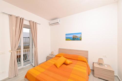 a bedroom with a bed with an orange blanket at La Perla Sul Mare in Forio d'Ischia