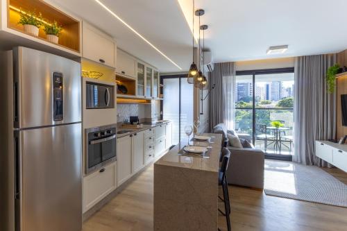 a kitchen with stainless steel appliances and a living room at Elegante Apartamento no Cambuí in Campinas