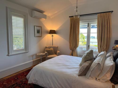 a bedroom with a bed and a chair and windows at Villa Victoria - Nelson in Nelson