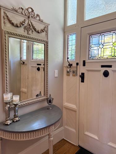a bathroom with a mirror and a table and a door at Villa Victoria - Nelson in Nelson
