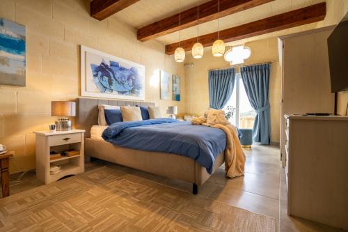 a bedroom with a large bed with blue sheets at Ajuga Luxury Boutique B&B in Qala