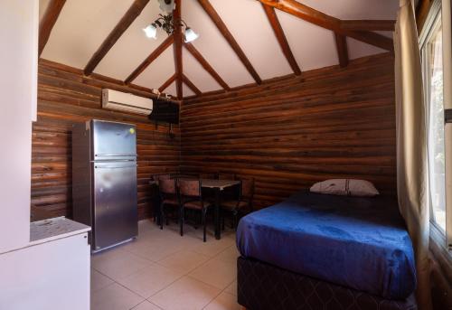 a bedroom with a bed and a table and a refrigerator at CABAÑAS EL CERRO in Ciudad Lujan de Cuyo