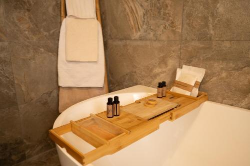 a bathroom with a bath tub with a wooden tray on it at Ajuga Luxury Boutique B&B in Qala