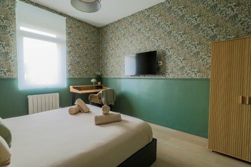 a bedroom with a bed and a tv on the wall at La Canopée - Bohemian - chic apartment in Lens