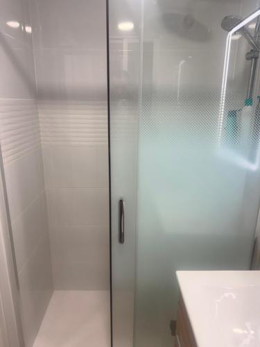 a shower with a glass door next to a sink at Habitación Doble con Aire cerca de la Playa in Benidorm