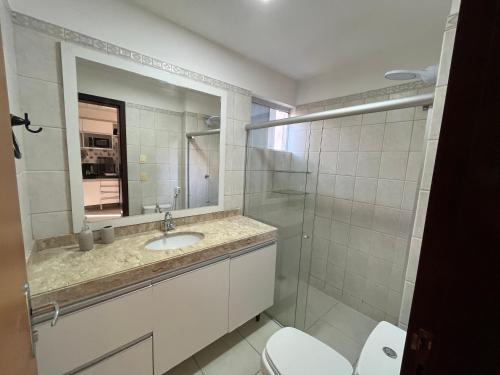 a bathroom with a sink and a toilet and a mirror at Apartamento Duplex vista mar Buzios in Nísia Floresta