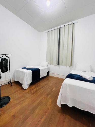two beds in a white room with wooden floors at Apto RUA DO LAZER in Santa Teresa
