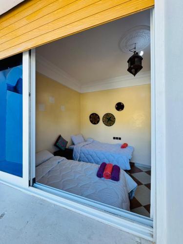 a bedroom with two beds and a large window at Vitamin taliouine appartement in Taghazout