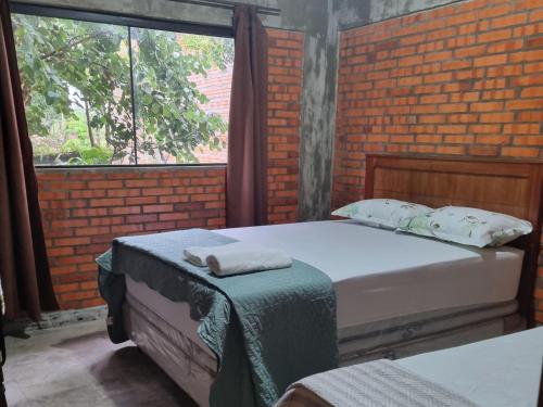 two beds in a room with a brick wall at Alojamiento Mariana y Ocho Oñondive in Villa Concepción
