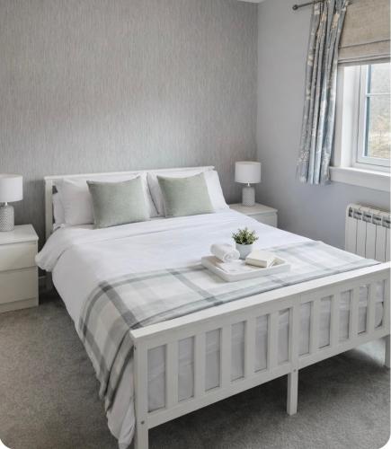 a bedroom with a large white bed with two tables at 6 Carn Dearg House in Aviemore