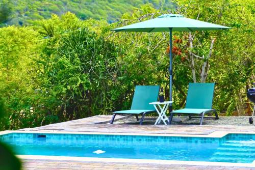 two chairs and an umbrella next to a swimming pool at Santirome Studio 2 - Cozy Westpunt Escape for Two in Westpunt