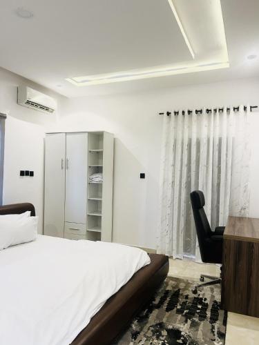 a bedroom with a bed and a desk and a chair at Dinems Apartment in Ikeja