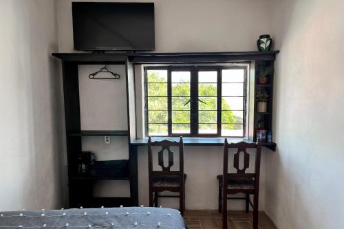a room with two chairs and a tv and a window at Habitación acogedora in Oaxaca City