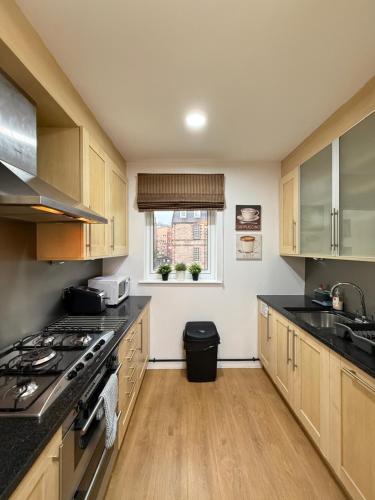a kitchen with wooden cabinets and a stove top oven at Holyrood Apartment with parking & lift access in Edinburgh