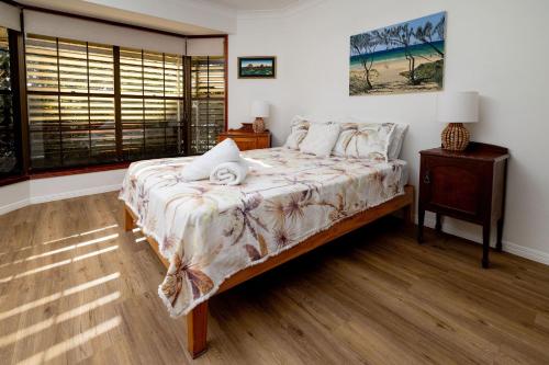 a bedroom with a bed with a nightstand and a window at Absolute Beach Front Home -Dogs, Surf, Relax, Bush in Kawana Waters