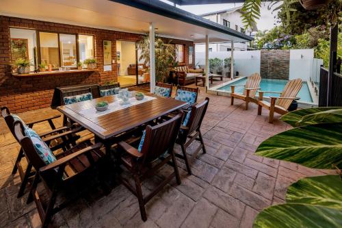 an outdoor patio with a wooden table and chairs at Absolute Beach Front Home -Dogs, Surf, Relax, Bush in Kawana Waters