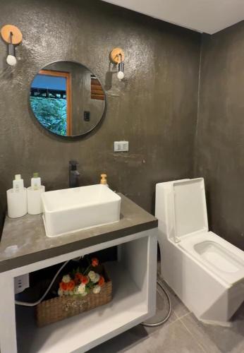 a bathroom with a sink and a mirror and a toilet at abot langit calatagan in Calatagan