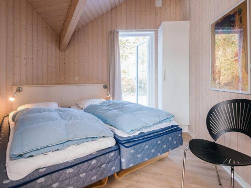 a bed with blue pillows in a room with a window at 14 person holiday home in Blåvand in Blåvand