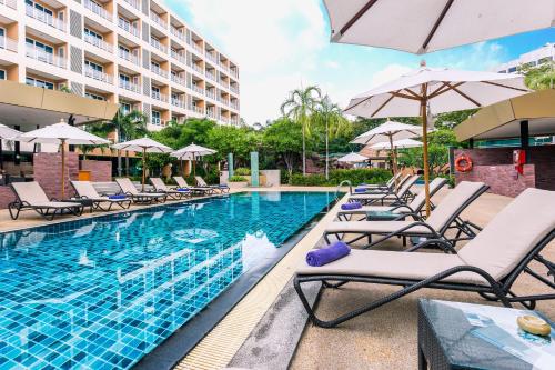 a pool at a hotel with lounge chairs and umbrellas at Nova Platinum Hotel in Pattaya South