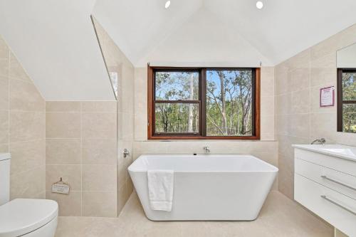 a white bathroom with a tub and a toilet at Standen Manor, Hunter Valley Country Estate & Stables in Belford