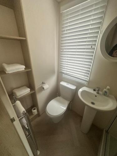 a white bathroom with a toilet and a sink at Moonstone in Lossiemouth