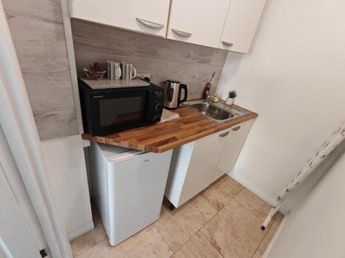 a small kitchen with a sink and a microwave at Lilac Studio - Self Contained One-Bed Studio Flat in Oxford