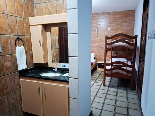 a bathroom with a sink and a mirror and a chair at Pousada Casa Grande in Bonito