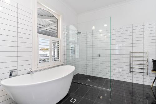 a white bathroom with a tub and a window at Altitude Studio in Martinborough