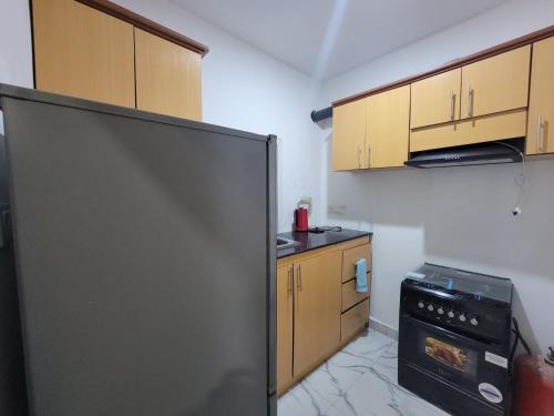 una cucina con frigorifero nero e mobili in legno di DALENT RESiDENCE a Brusubi