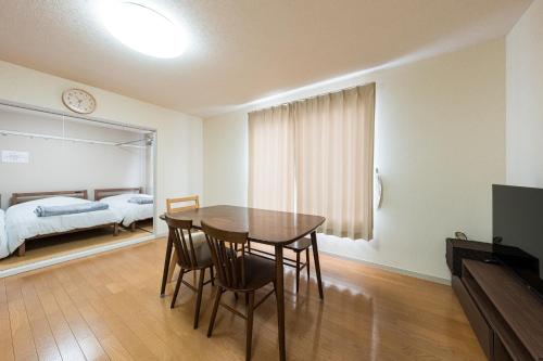 a dining room with a table and chairs and a bedroom at アルカディアｋ in Aomori