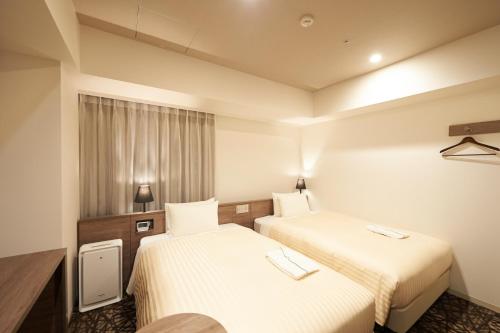 a hotel room with two beds and a window at Sotetsu Fresa Inn Ginza-Nanachome in Tokyo