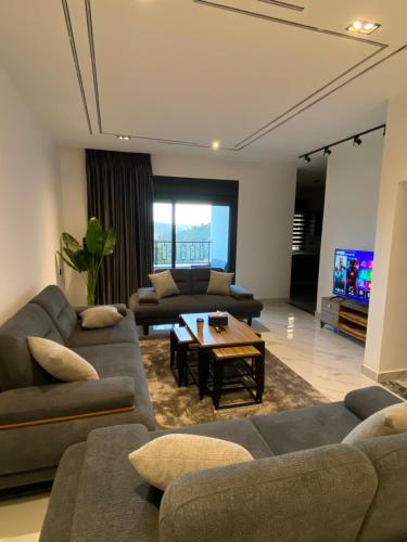 a living room with couches and a table and a tv at دار المكارم للشقق الفندقية الفاخره in Jerash