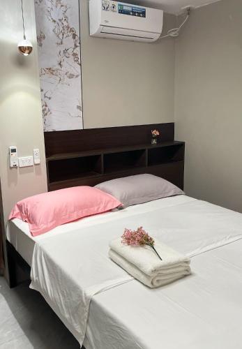 a bed with white sheets and pink pillows and flowers on it at Nadi Easy Home Near McDonalds in Nadi