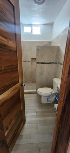 a bathroom with a toilet and a wooden door at Meztli Beach House in La Manzanilla