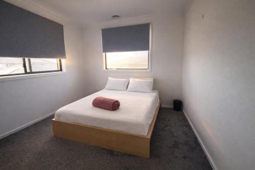 a bedroom with a bed with white sheets and two windows at Spacious Private 4BR Upper Floor Sleeps 8 Spa Free parking in Werribee