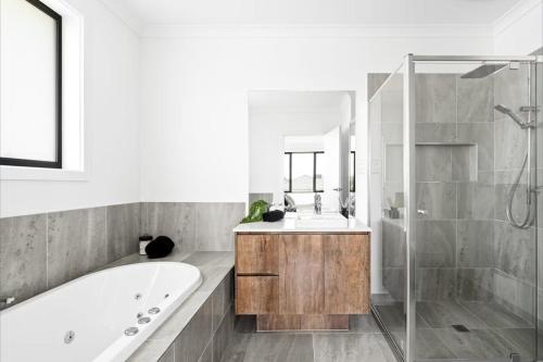a bathroom with a tub and a sink and a mirror at Spacious Private 4BR Upper Floor Sleeps 8 Spa Free parking in Werribee