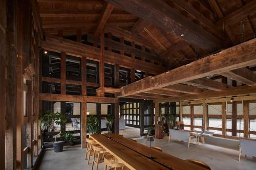 a large room with wooden ceilings and tables and chairs at 泊まれる文化交流施設 盆宿U bon-yadoU in Nishimonai