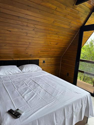 a bedroom with a white bed with a wooden ceiling at Refúgio do Morro - cabana 2 in Torres
