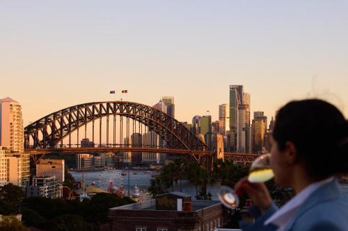 a woman drinking a glass of wine in front of a bridge at View Sydney in Sydney