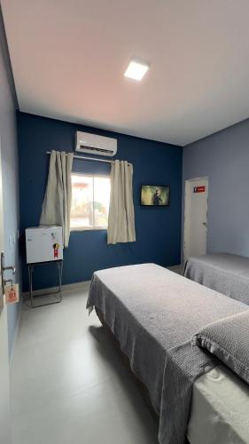 a blue bedroom with two beds and a window at Hotel e Restaurante Santa Isabel in São Raimundo Nonato