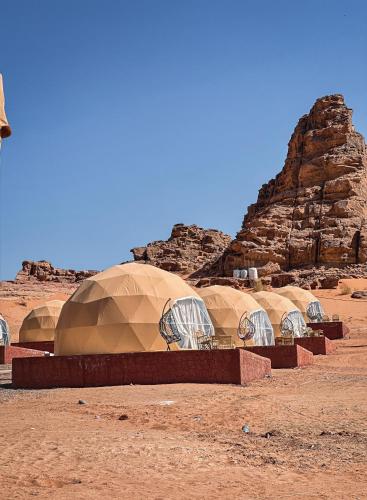 a row of domes in the middle of a desert at Red sand tent in Disah