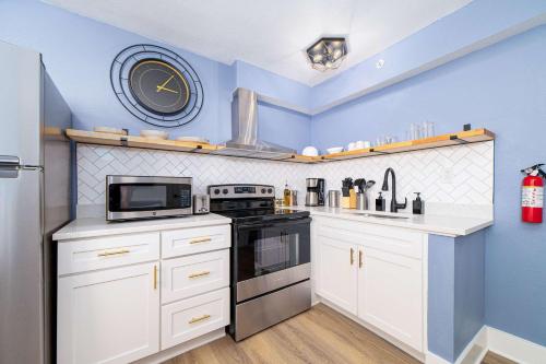 a kitchen with white cabinets and a clock on the wall at Sojourn's Harborage Pet-Friendly # 3 in Norfolk