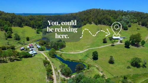 an aerial view of a house on a hill with a lake at Hinterland Hideaway Farm Stay in Wolvi